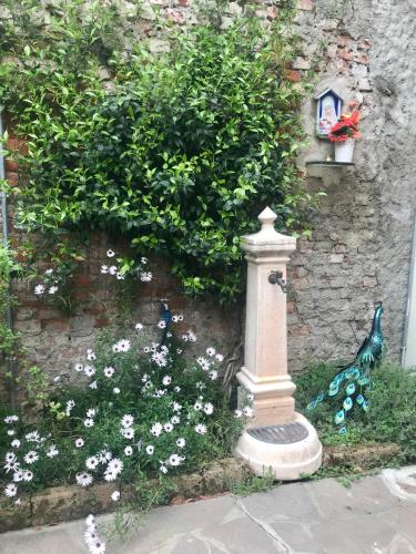 a bird statue next to a stone wall with flowers at B&B Corte sul Naviglio CIN I T 0 1 5 0 7 0 C 1 3 X U I L Q C V in Cernusco sul Naviglio