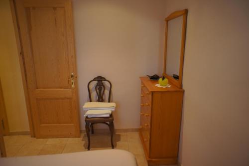 ein Schlafzimmer mit einer Kommode, einem Stuhl und einem Spiegel in der Unterkunft Ca La Paletes in Cornudella de Montsant