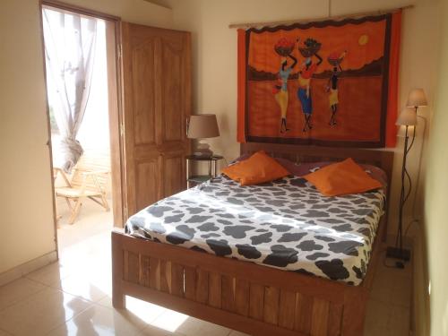 a bedroom with a bed with a painting on the wall at Chez medzo et patou in Poponguine