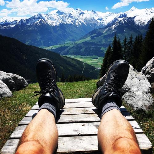 a man with his feet up on a wooden path with mountains at Piesendorf Pad - Oberbichl in Piesendorf