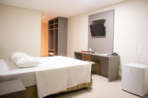 1 dormitorio con 1 cama, escritorio y TV en Orla Morena Park Hotel, en Campo Grande