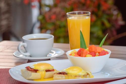 a plate with a sandwich and a bowl of fruit and a cup of coffee at La Riviera Hotel in San Antonio