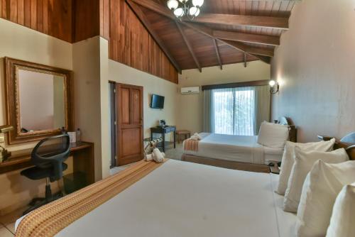a bedroom with two beds and a desk and a mirror at La Riviera Hotel in San Antonio