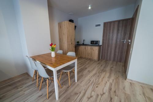 a dining room with a wooden table and chairs at Apartamenty Prusa in Mikołajki