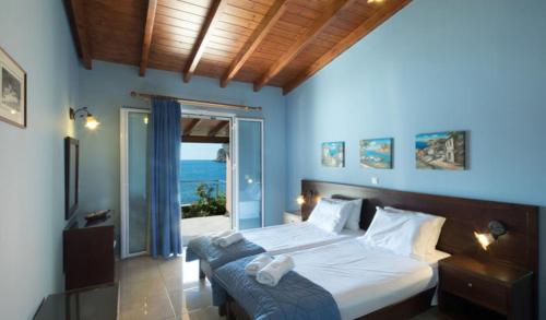 a bedroom with a bed with a view of the ocean at Yiannis Seafront Villa Paleokastritsa in Paleokastritsa