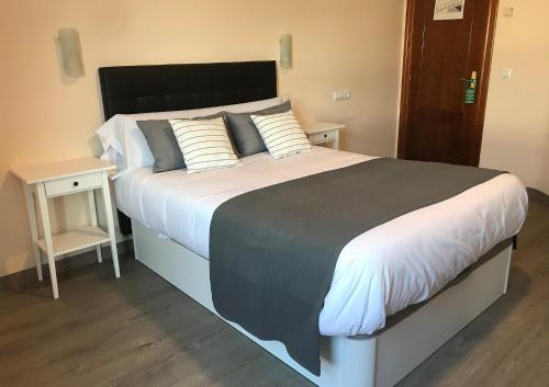 een slaapkamer met een groot bed met witte lakens en kussens bij HOTEL DEL NORA in Noreña