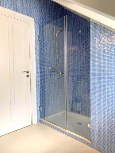 una doccia in vetro in un bagno piastrellato di blu di Residence Lagos a Lagos