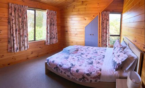 ein Schlafzimmer mit einem Bett in einer Holzhütte in der Unterkunft Lake view family Lodge up tp 14 people in Rotorua