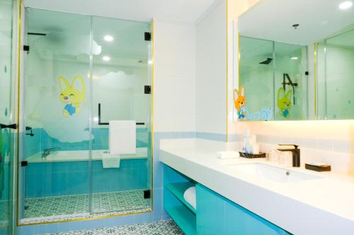 a bathroom with a glass shower and blue cabinets at Jpark Island Resort & Waterpark Cebu in Mactan