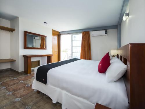 a bedroom with a large white bed with red pillows at Suites de Reyes in Irapuato