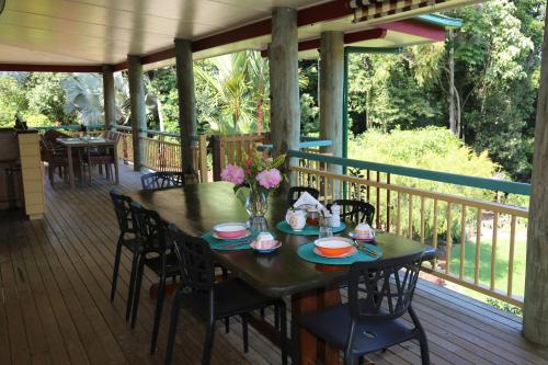 a wooden deck with a table with flowers on it at Licuala Lodge in Mission Beach