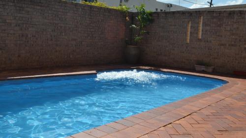 a large blue swimming pool next to a brick wall at Matilda Motel in Bundaberg