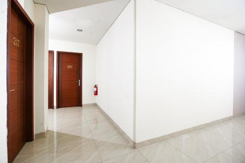 a hallway with white walls and wooden doors at RedDoorz near Palembang Trade Center 3 in Sukarami