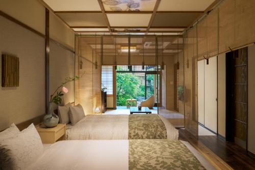 a bedroom with two beds and a large window at Nazuna Kyoto Nijo-jo in Kyoto