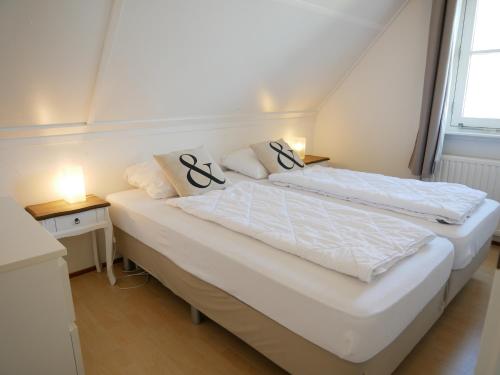 een slaapkamer met twee bedden en twee nachtkastjes bij Villa Buiten 58 in Callantsoog