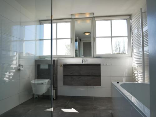 een badkamer met toilet, wastafel en bad bij Villa Buiten 58 in Callantsoog