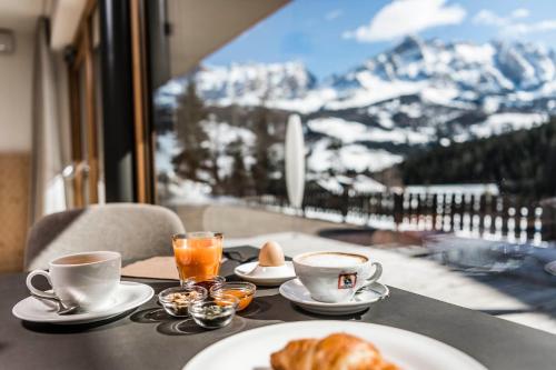 a table with two cups of coffee and croissants on at Garni La Ciasota 3s in La Villa