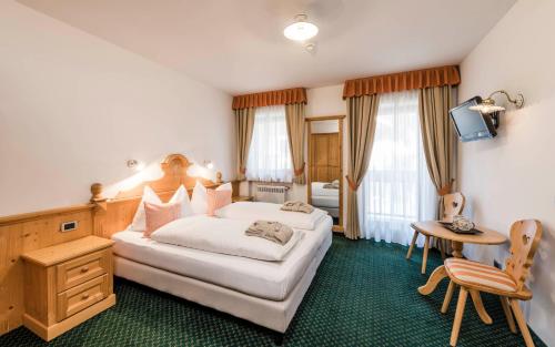 una habitación de hotel con una cama grande y una mesa en Garni La Ciasota 3s, en La Villa