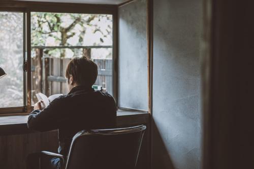 a woman sitting in a chair looking out a window at NIPPONIA Kosuge Village in Kosuge