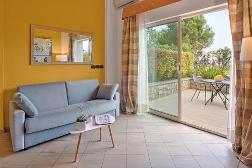a living room with a couch and a sliding glass door at Aregai Marina Hotel & Residence in Santo Stefano al Mare