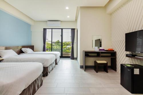 a hotel room with three beds and a television at 98Inn in Xiaoliuqiu