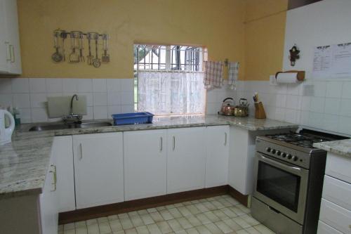 a kitchen with white cabinets and a stove top oven at Absolute Leisure Cottages in Machadodorp