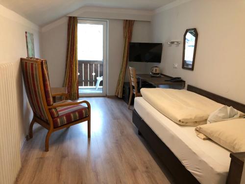 a bedroom with a bed and a chair and a desk at Hotel Bavaria in Bad Wiessee