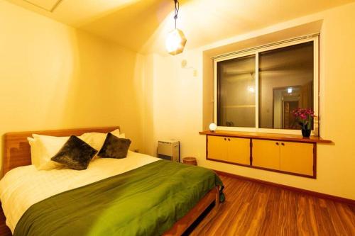 a bedroom with a large bed and a window at The COMFORIA in Sapporo
