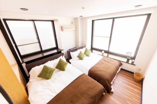 two beds in a room with two large windows at The COMFORIA in Sapporo