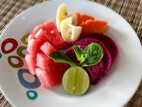 a white plate with fruits and vegetables on a table at Wide Sands Beach Retreat in Pulukan