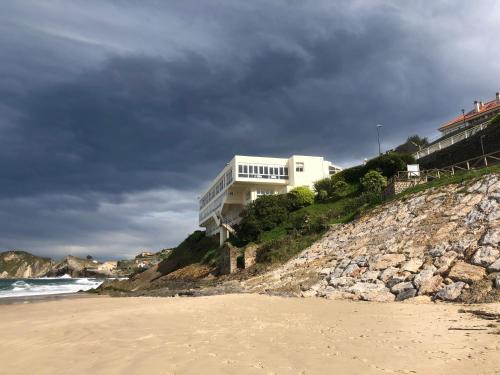 a white house on a hill next to the beach at Hotel Josein in Comillas
