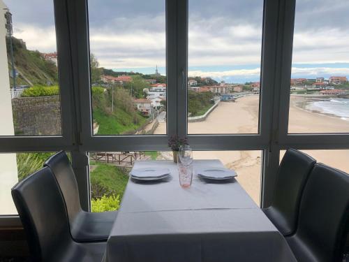 a table in a restaurant with a view of the beach at Hotel Josein in Comillas
