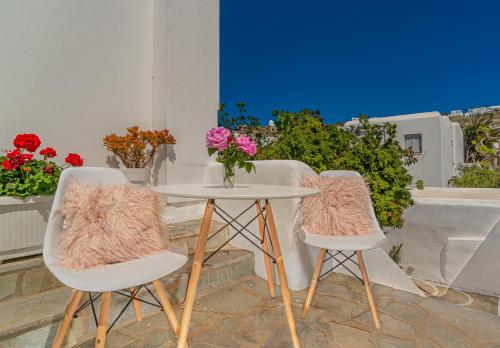 two chairs and a table with a vase of flowers at Dimelal Mykonos Town Apartments in Mýkonos City