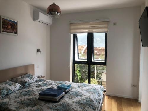 sypialnia z łóżkiem z niebieską pościelą i oknem w obiekcie Apartments Bane w mieście Herceg Novi