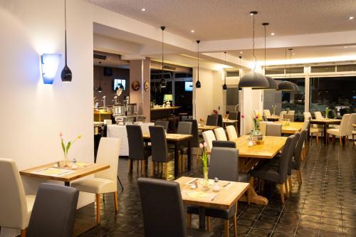 a dining room with wooden tables and chairs and a restaurant at Anor Hotel & Conference Center Frankfurt Airport in Mörfelden-Walldorf