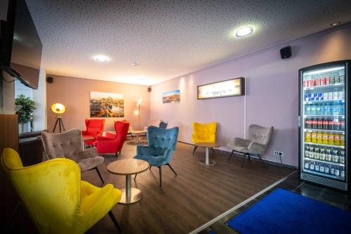 a waiting room with colorful chairs and tables at Anor Hotel & Conference Center Frankfurt Airport in Mörfelden-Walldorf