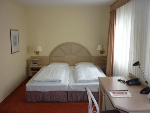 ジンデルフィンゲンにあるAbakus-Hotelのベッドとデスクが備わるホテルルームです。