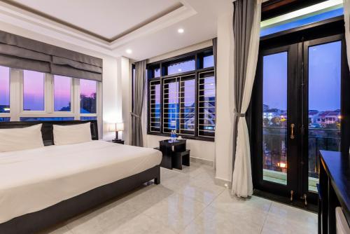a bedroom with a large bed and large windows at Flamingo Villa Homestay - Big Rooms with Balcony - Close to Hoi An Old Town 200m & Temple Bridge - Large Outside Pool for Sun Bathing in Hoi An