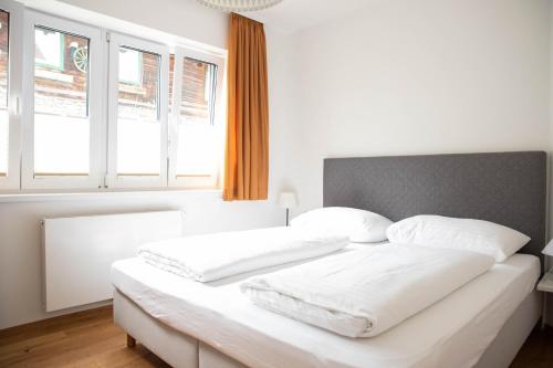 łóżko z białymi prześcieradłami i poduszkami w sypialni w obiekcie Appartements Freiraum w Schladming
