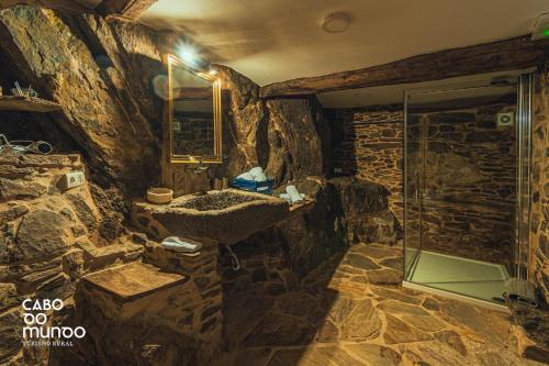 a stone bathroom with a sink and a shower at Cabo Do Mundo Casa Rural in Chantada