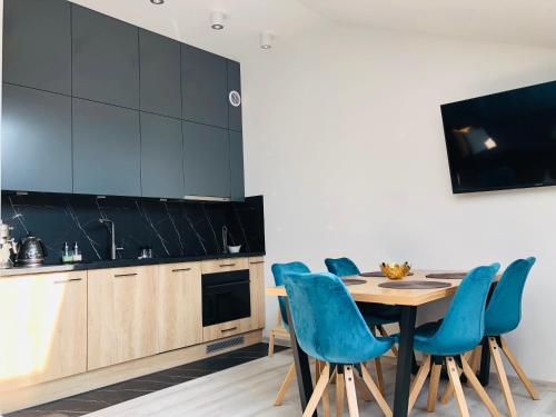 a kitchen with a wooden table and blue chairs at Olympic Residence in Szczyrk