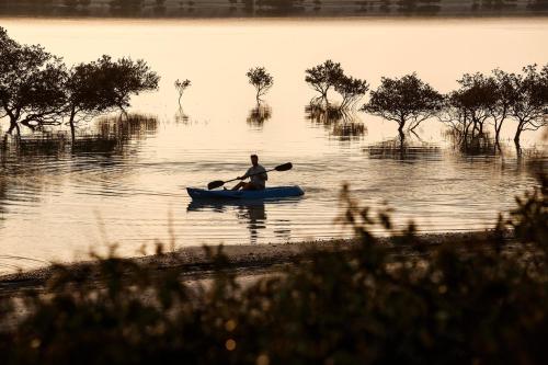 a man is paddling a canoe on a lake at Anantara Desert Islands Resort & Spa in Da‘sah
