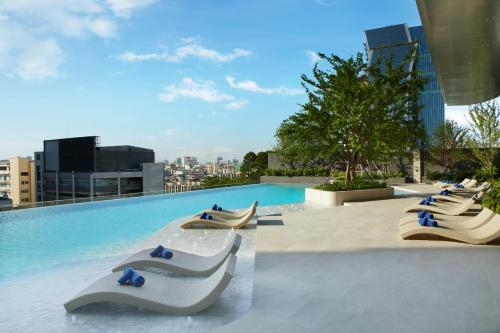 a swimming pool with lounge chairs on top of a building at Somerset Rama 9 Bangkok in Bangkok