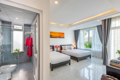 a bedroom with two beds and a bathroom at Flamingo Villa Homestay - Big Rooms with Balcony - Close to Hoi An Old Town 200m & Temple Bridge - Large Outside Pool for Sun Bathing in Hoi An