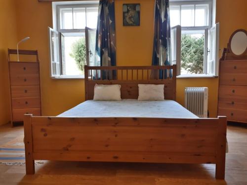 a bedroom with a wooden bed and two windows at Country house Horné Držkovce in Horné Držkovce