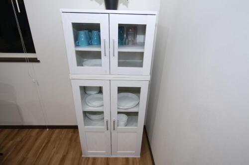 a white cabinet with plates and dishes in it at Tiz wan 岩屋あわじ in Awaji