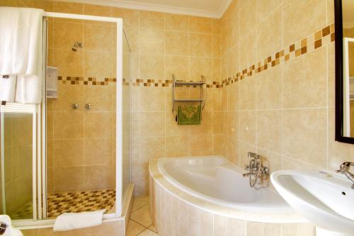 uma casa de banho com uma banheira, um chuveiro e um lavatório. em Seagull Lodge em Richards Bay