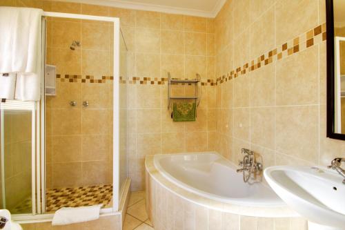a bathroom with a tub and a shower and a sink at Seagull Lodge in Richards Bay