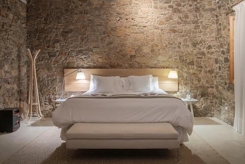 a bedroom with a large bed and a stone wall at Charco Hotel in Colonia del Sacramento
