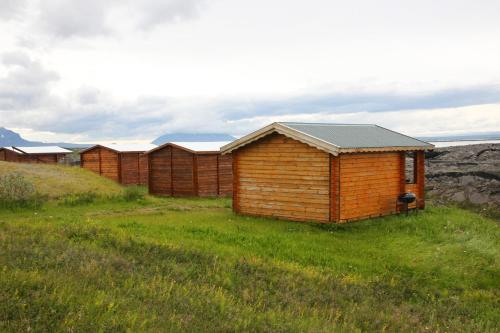 a row of wooden huts in a grass field at Hlíd Huts in Myvatn